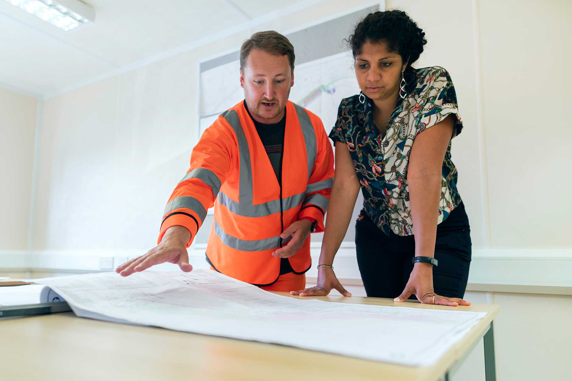 business project manager in a fluro vest explains procurement to trainer