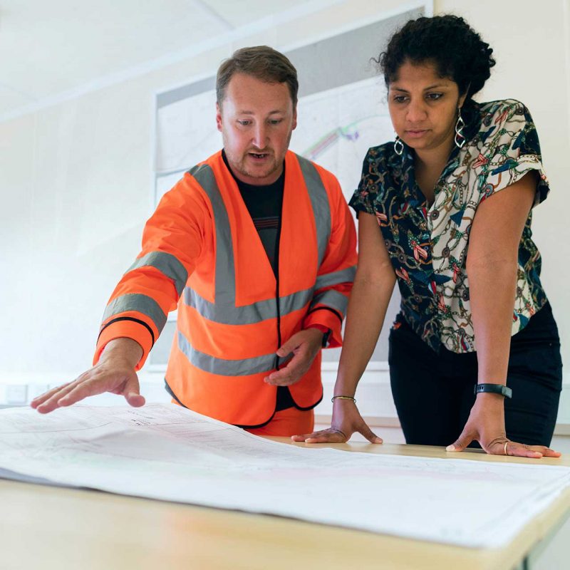 business project manager in a fluro vest explains procurement to trainer